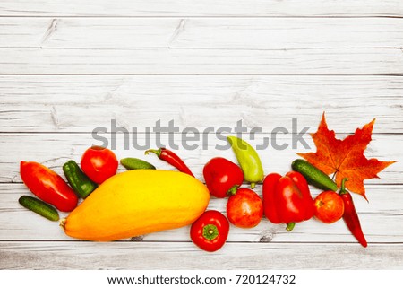 Vegetables and autumn leaves on bright wooden table.