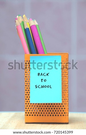 Colorful pencils in the case with words written BACK TO SCHOOL on sticky note. Education concept.