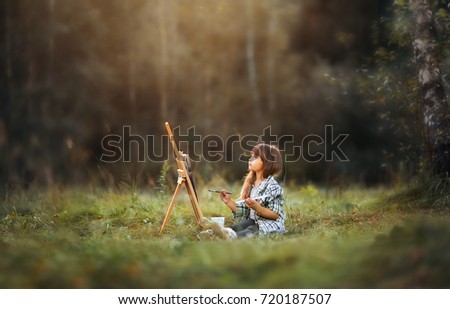 Little girl painting at easel in autumn park 