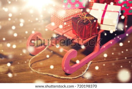 holidays, christmas, presents, new year and celebration concept - close up of many little gift boxes on red wooden sleigh on wooden table