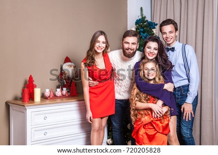 Picture showing happiness family, celebrating christmas at home, looking at camera and posing for family picture. Indoor, studio shot