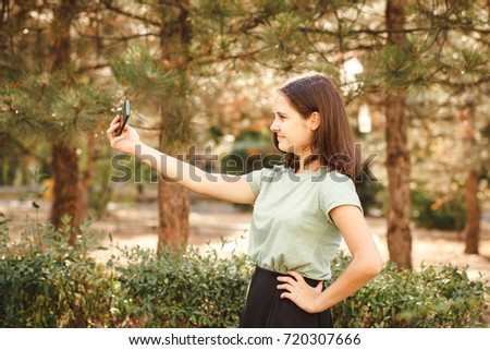A young teenage girl outdoors doing selfie. Space for text.The girl takes pictures of herself
