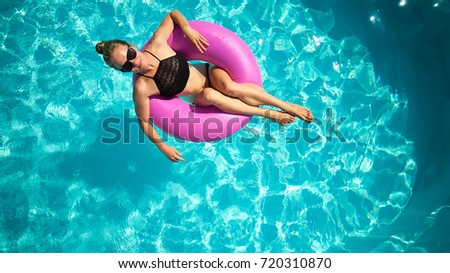 top view of young female swim with inflatable pink ring  in pool