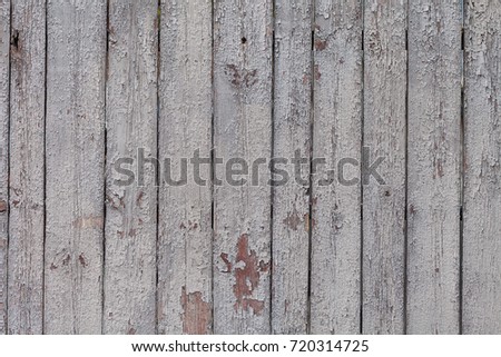 Old wooden fence with cracked paint in the village. Background vintage texture