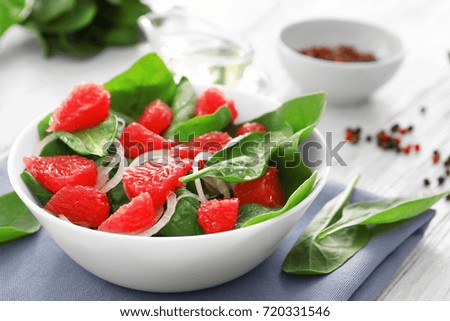 Plate of salad with spinach and grapefruit on table