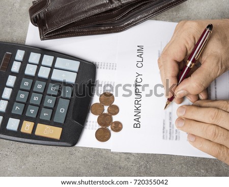 Bankruptcy concept image of a pen, calculator and coins on financial documents.