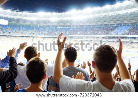 Football- soccer fans support their team and celebrate goal in full stadium with open air with nice sky.-blur picture.