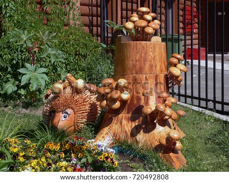 Wooden sculpture in the city park. This is a hedgehog and mushrooms on hemp, handmade