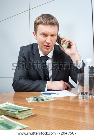 Businessman with pack of one hundred dollars calls in office
