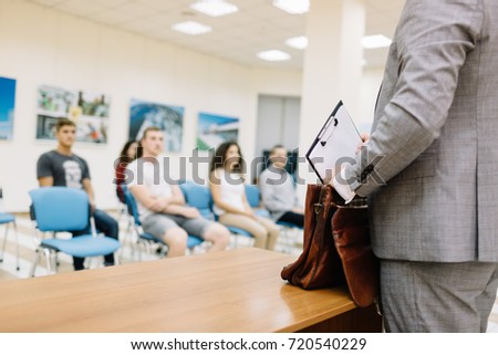 Close-up picture businessman putting papers in a brown classy briefcase on a blurred office background. Copy space.