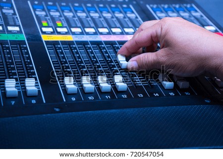 Someone hand working on Volume slide audio mixer in the control room of television broadcast. Mixdown 