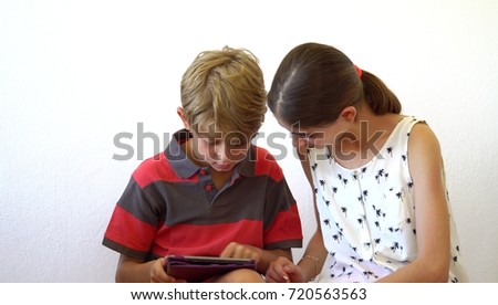 Happy brother and sister playing tablet. Little kids play. Happy family