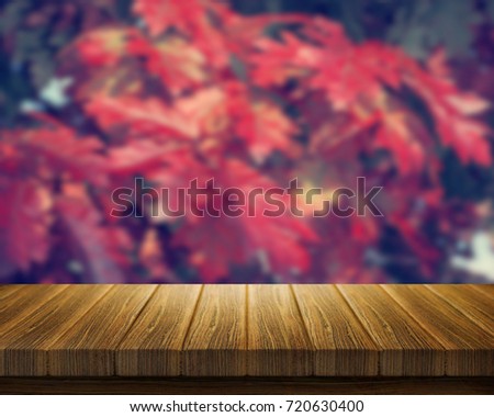 3D render of a wooden table with a defocussed image of red fall leaves