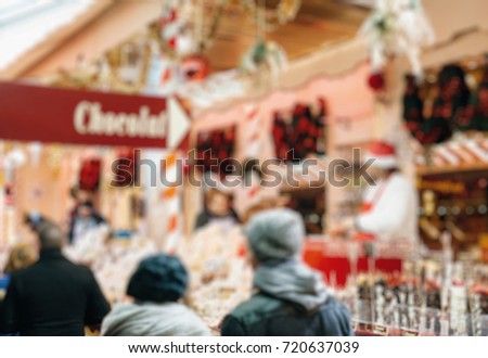 Defocused sillhuettes of Illuminated Christmas fair kiosk market stall with loads of lovely and sweet christmas chocolate