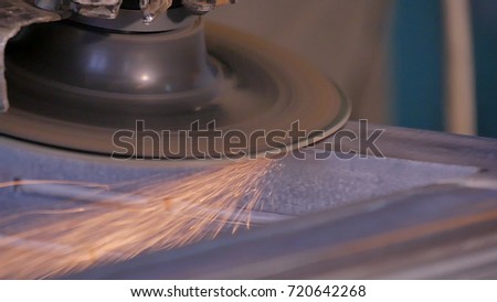 Craftsman sawing metal with disk grinder in workshop. Grinding metal with sparks flying. Electric wheel grinding on steel structure in factory Low speed shutter . metal grinding with orange flying