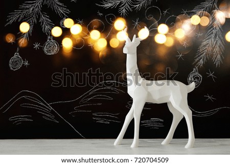 White reindeer on wooden table over chalkboard background whith hand drawn chalk illustrations
