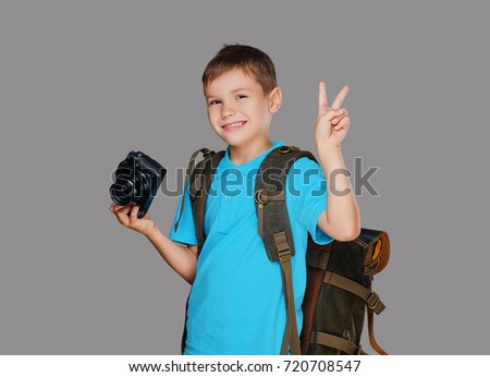 Preschooler boy taking pictures with a professional photo camera. Isolated on grey background.