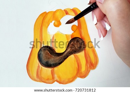 The process of drawing a pumpkin with watercolor on white paper.