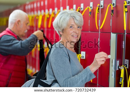 portrait of senior woman putting coin in locker