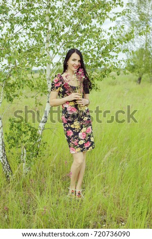 A beautiful girl in a summer pink dress is near a tree
