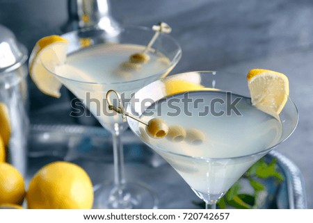 Glasses of lemon drop martini with olives on blurred background, closeup