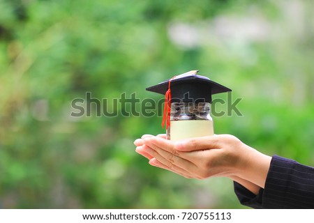 Woman hand holding coins money in glass bottle with graduates hat on natural green background, Saving money for education concept Royalty-Free Stock Photo #720755113