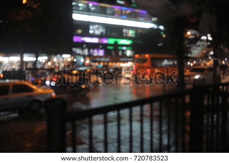 Blur focus from building, traffic and car light in Bangkok city at roadside and raining.