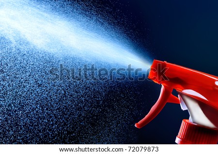 spray bottle - lighted while spraying on dark background Royalty-Free Stock Photo #72079873