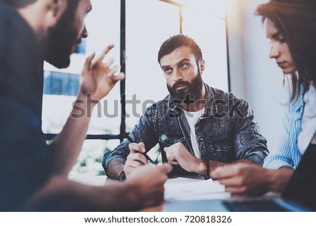 Young business people discussing new business project in modern office.Group of three coworkers brainstorming at meeting room.Horizontal,blurred background