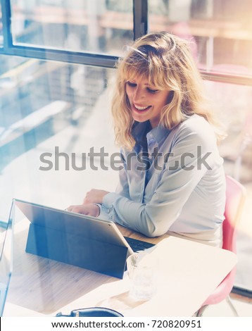 Happy beautiful businesswoman working at the modern office loft.Coworker using electronic touch tablet computer on sunny workplace.Vertical. Blurred background