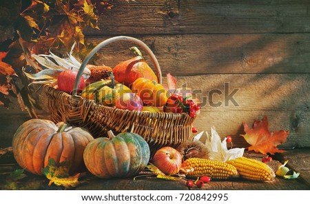 Thanksgiving pumpkins and falling leaves on rustic wooden table in barn