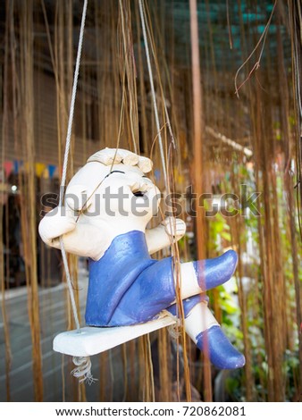 Cute happiness clay dolls sitting on swings  decoration in the garden.
