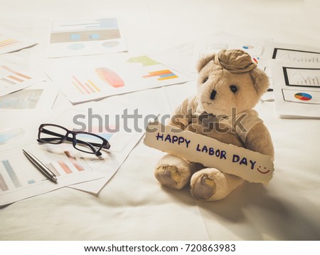 Happy Labor Day concept - Teddy Bear on white bed with business charts in background