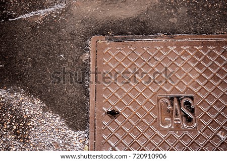 Metal brown rusty manhole cover on a pedestrian walkway