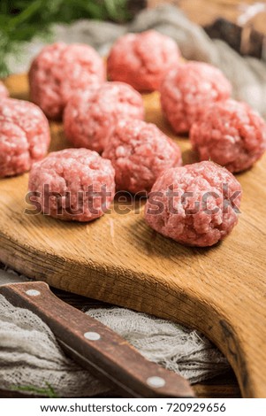 Raw meatballs on the wooden cutting board. Small depth of field.