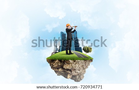 Engineer man standing on green floating island in blue sky