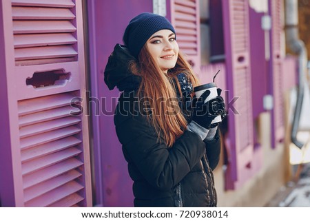 girl walking on snow-covered town, drinking coffee, photographed on the phone and riding on a sled