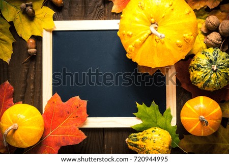 Festive autumn background or greeting card. Pumpkins leaves and chalkboard on wooden background. Top view copy space.