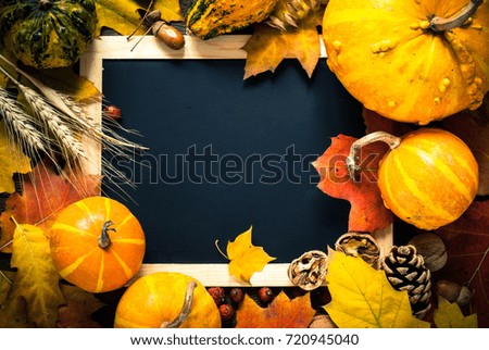 Thanksgiving day background. Autumn vegetables nuts and leaves around chalkboard. Top view.