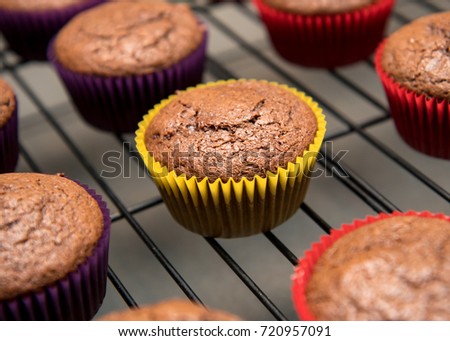 Cupcake in vibrant yellow wrapper cooling on rack Royalty-Free Stock Photo #720957091