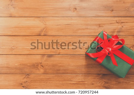 Present for any holiday concept. Gift box, top view with copy space on wood table surface background. Package with red satin ribbon bow for christmas, valentine day or birthday
