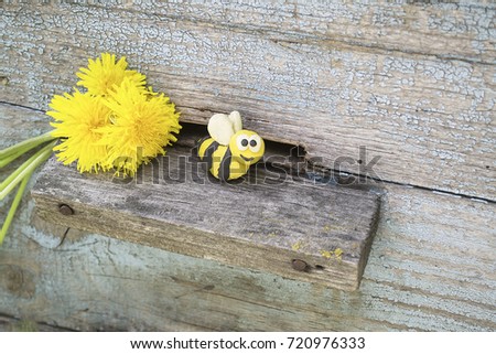 Plasticine world . handmade bee on on wooden background.Dandelion flowers .  handmade honeybee in the hive . Plasticine world