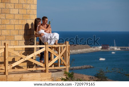 Happy couple on the balcony of a house on the background of the sea
