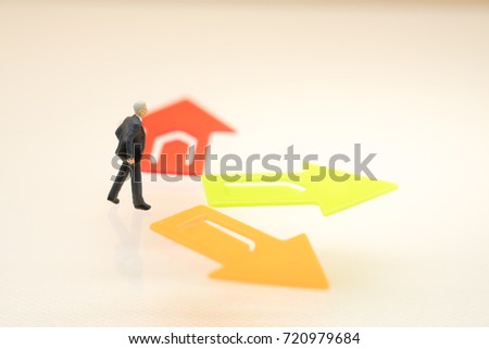 Miniature people: Businessman standing in front of arrow pathway choice using as Business decision concept.