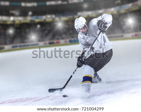 ice hockey player in action kicking with stick in front of big modern hockey arena with flares and lights