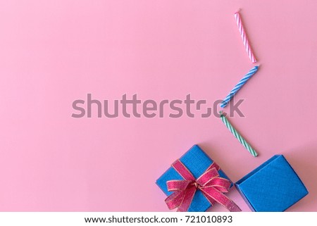 Colorful candles from opened blue gift box on pink background for celebration event