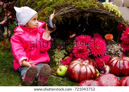 Adorable little girl having fun on a pumpkin patch on beautiful autumn day outdoors. Happy child playing in autumn park.
