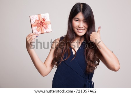 Young Asian woman thumbs up with a gift box on gray background