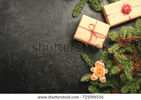 Christmas background with decorations, fir tree, gift boxes and gingerbread on black background, top view with copy space