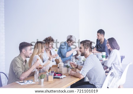 Young happy coworkers talking and eating lunch together Royalty-Free Stock Photo #721101019